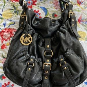 Black Michael Kors purse with gold accents.